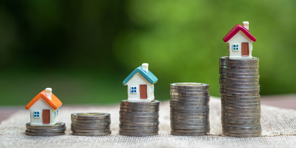 Mini,House,Standing,On,A,Heap,Of,Coins.,The,Concept