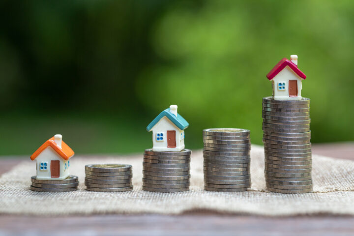 Mini,House,Standing,On,A,Heap,Of,Coins.,The,Concept