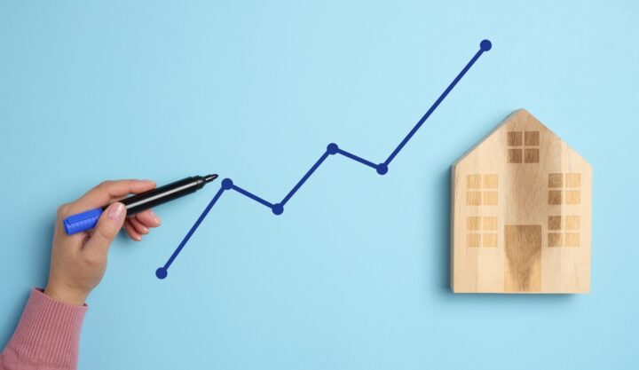 A,Wooden,House,And,A,Woman’s,Hand,With,A,Marker